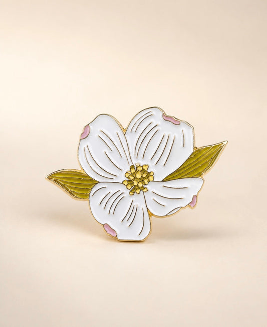 The Plant Ecologist flowering dogwood hard enamel pin featuring white petals with pink tips and a golden center.