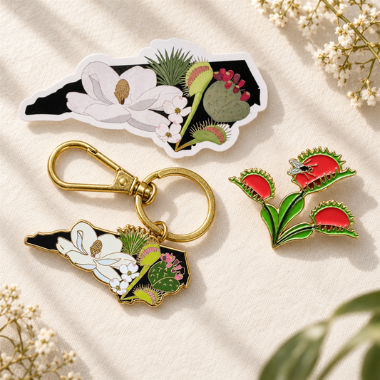 The Plant Ecologist Venus Flytrap pin, NC native plants keychain, and die-cut sticker set on a textured fabric.
